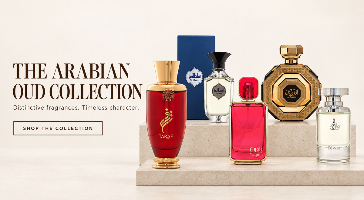 A curated collection of Arabian oud fragrances displayed on a light stone pedestal against a warm off-white background. The collection includes Taraf (a tall red bottle with gold trim), Lailah (a red rectangular bottle), a gold octagonal bottle, and two clear glass bottles, alongside their blue and gold packaging boxes.
