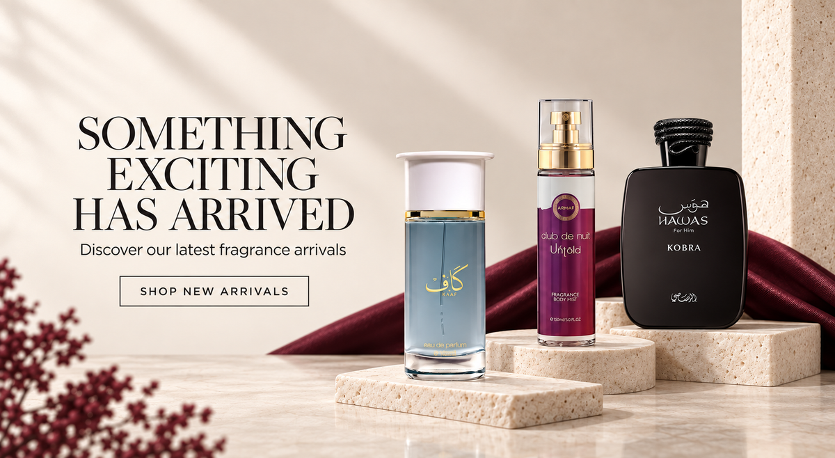 Three perfume and fragrance bottles displayed on stone pedestals with a dark red fabric backdrop, alongside promotional text reading 'SOMETHING EXCITING HAS ARRIVED' and a 'SHOP NEW ARRIVALS' button.