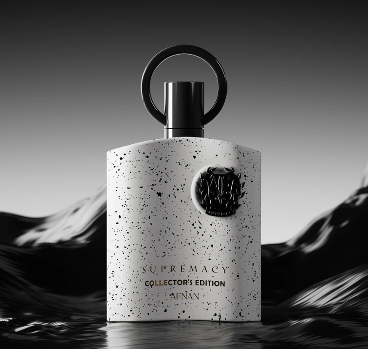 A bottle of Afnán Supremacy Collector's Edition fragrance, featuring a textured white bottle with black speckles, a black circular cap handle, and gold lettering, set against a dark, moody mountain background.