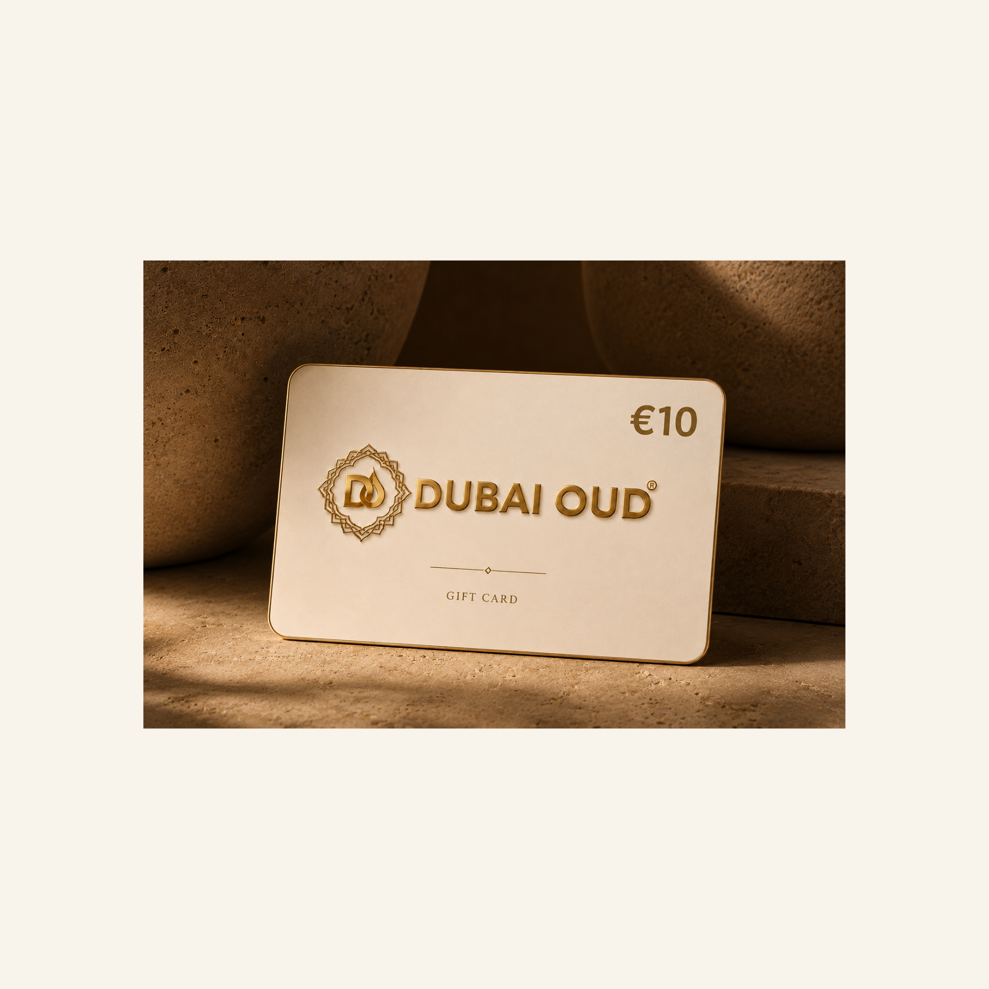 A Dubai Oud €10 gift card with gold foil lettering and logo, displayed on a textured beige stone surface with a warm, earthy background.
