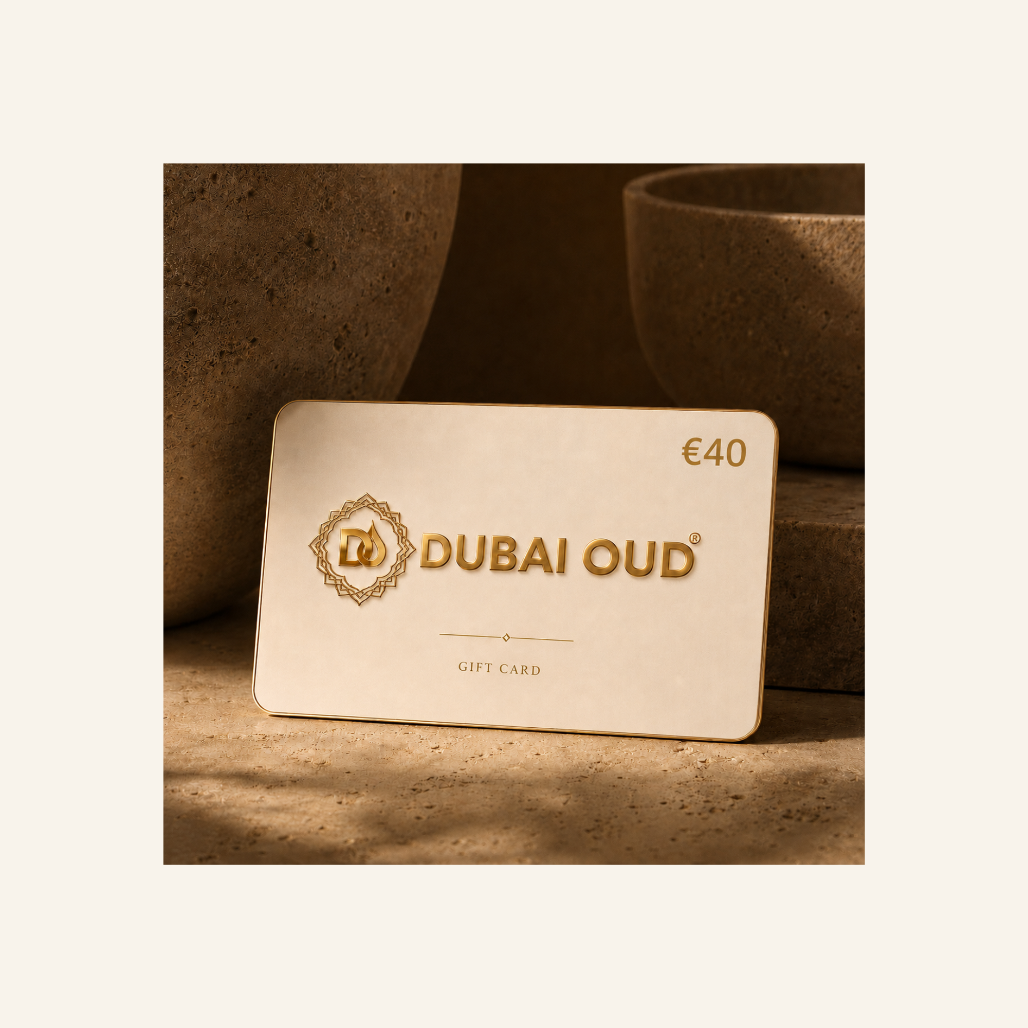 A Dubai Oud €40 gift card in a warm cream color with gold foil lettering and logo, displayed on a textured stone surface with a warm, earthy background.