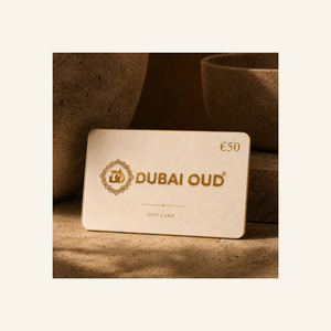 A Dubai Oud €50 gift card with gold lettering and logo, displayed on a textured stone surface with warm, earthy background props.